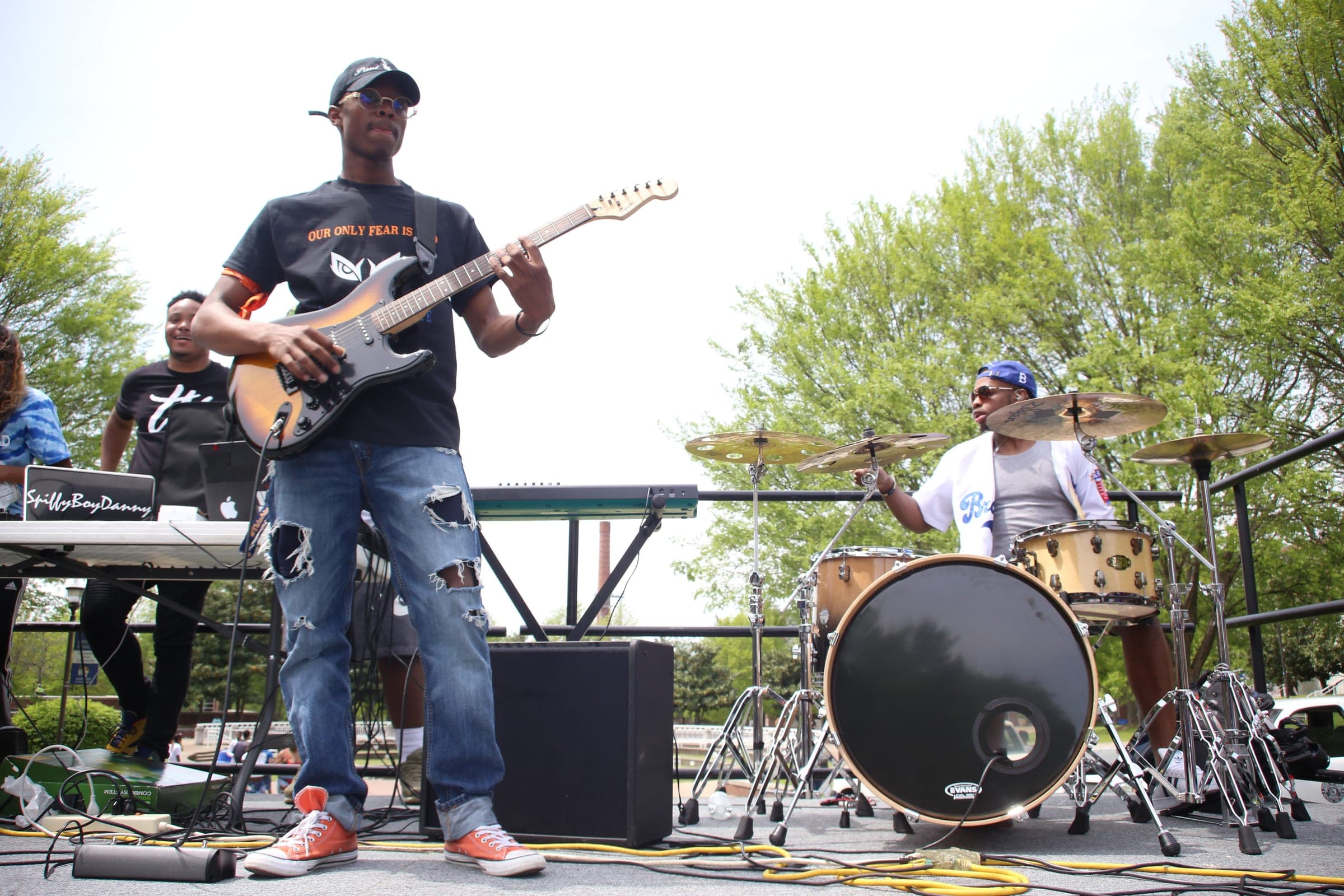 Paul Neil playing a sunburst Stratocaster on an outdoor stage with his band